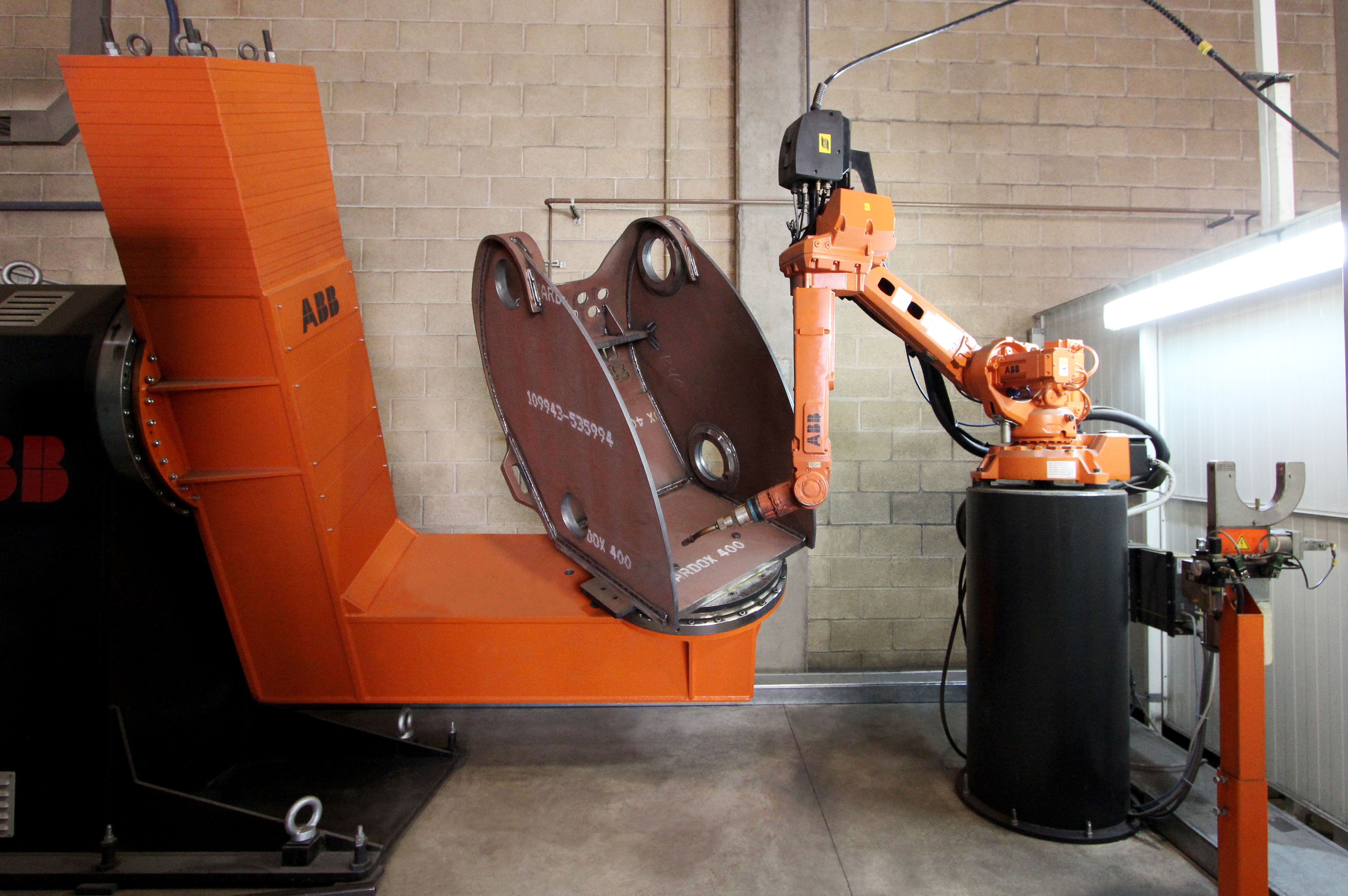 Orange industrial robot alongside a steel component in a workshop